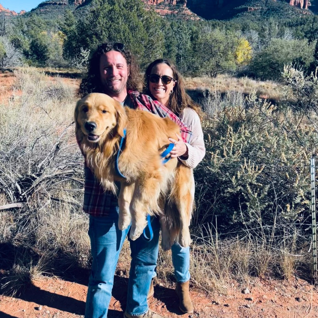 couple holds golden retriever with sedona in background