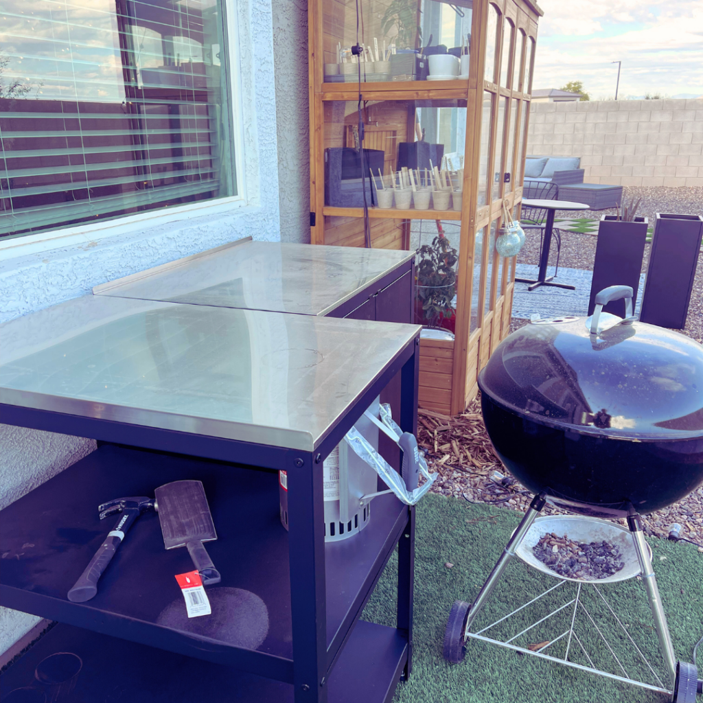 outdoor food prep and grill area with greenhouse in the background