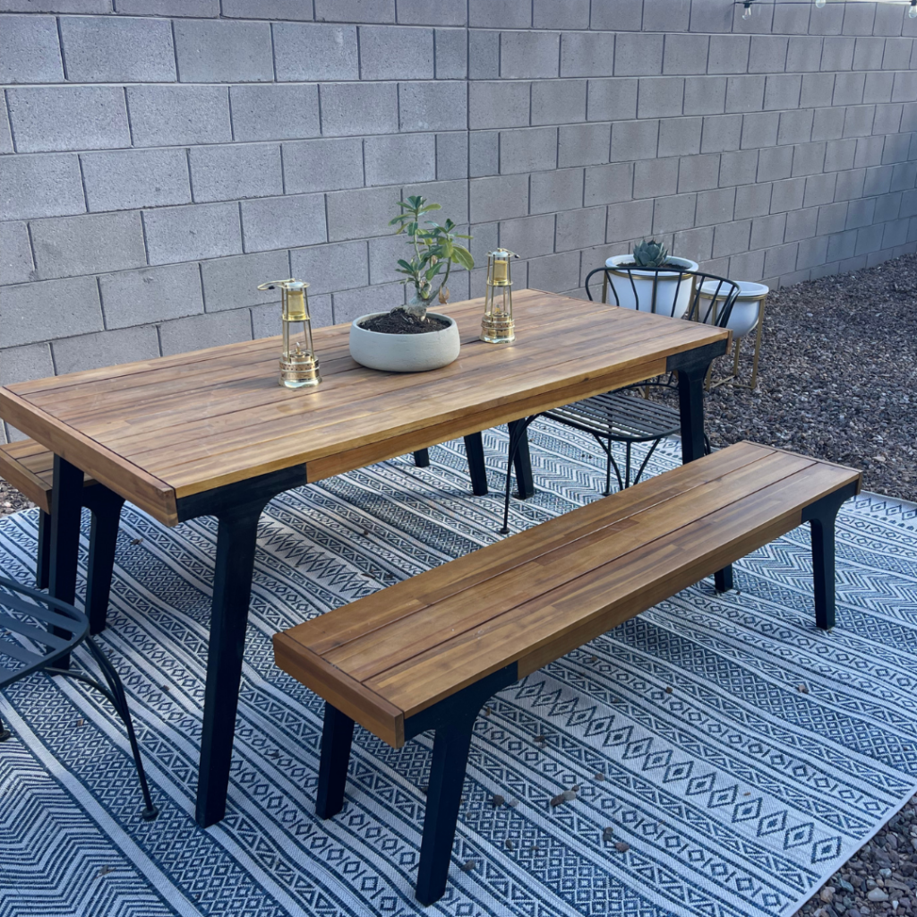 our dining area in our AZ backyard with table, benches, desert rose, and lanterns